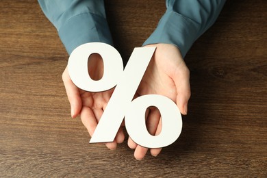 Woman holding percent sign at wooden table, closeup