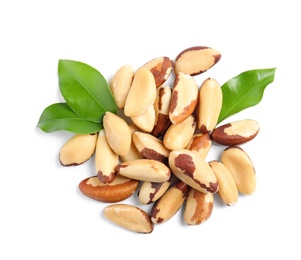 Brazil nuts with green leaves on white background, top view