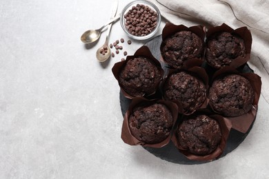 Photo of Tasty chocolate muffins on light table, flat lay. Space for text