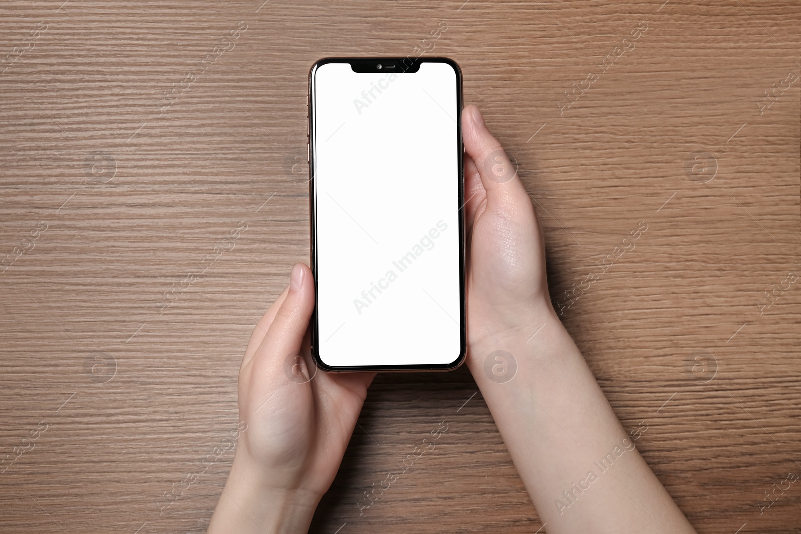 Photo of Woman holding smartphone with blank screen at wooden table, top view. Mockup for design