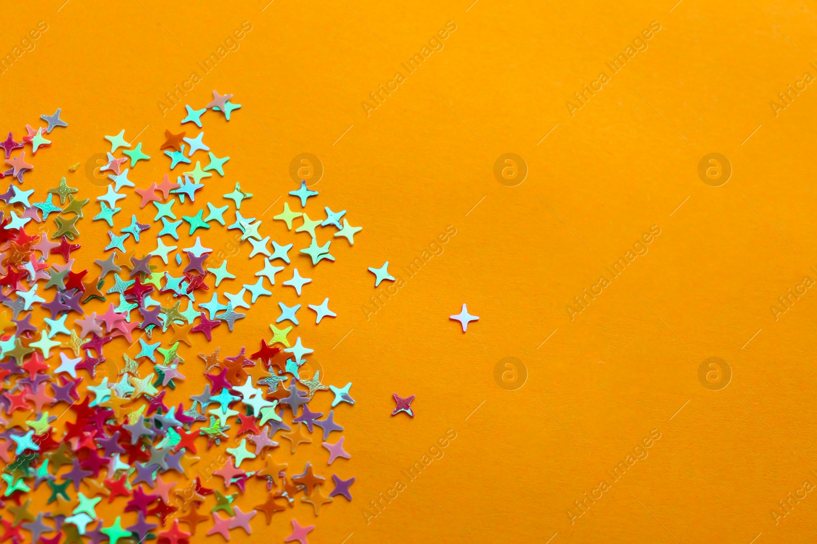 Photo of Shiny bright colorful glitter on pale orange background. Space for text