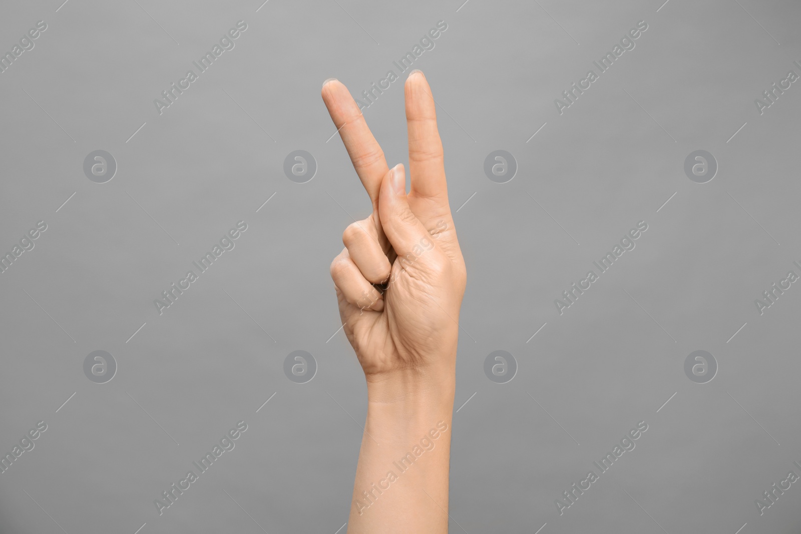 Photo of Woman showing K letter on grey background, closeup. Sign language