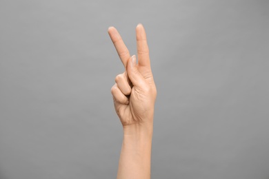 Photo of Woman showing K letter on grey background, closeup. Sign language