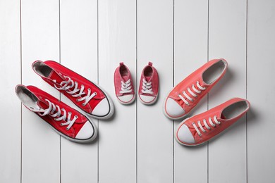 Photo of Stylish sneakers for all family members on white wooden background, flat lay