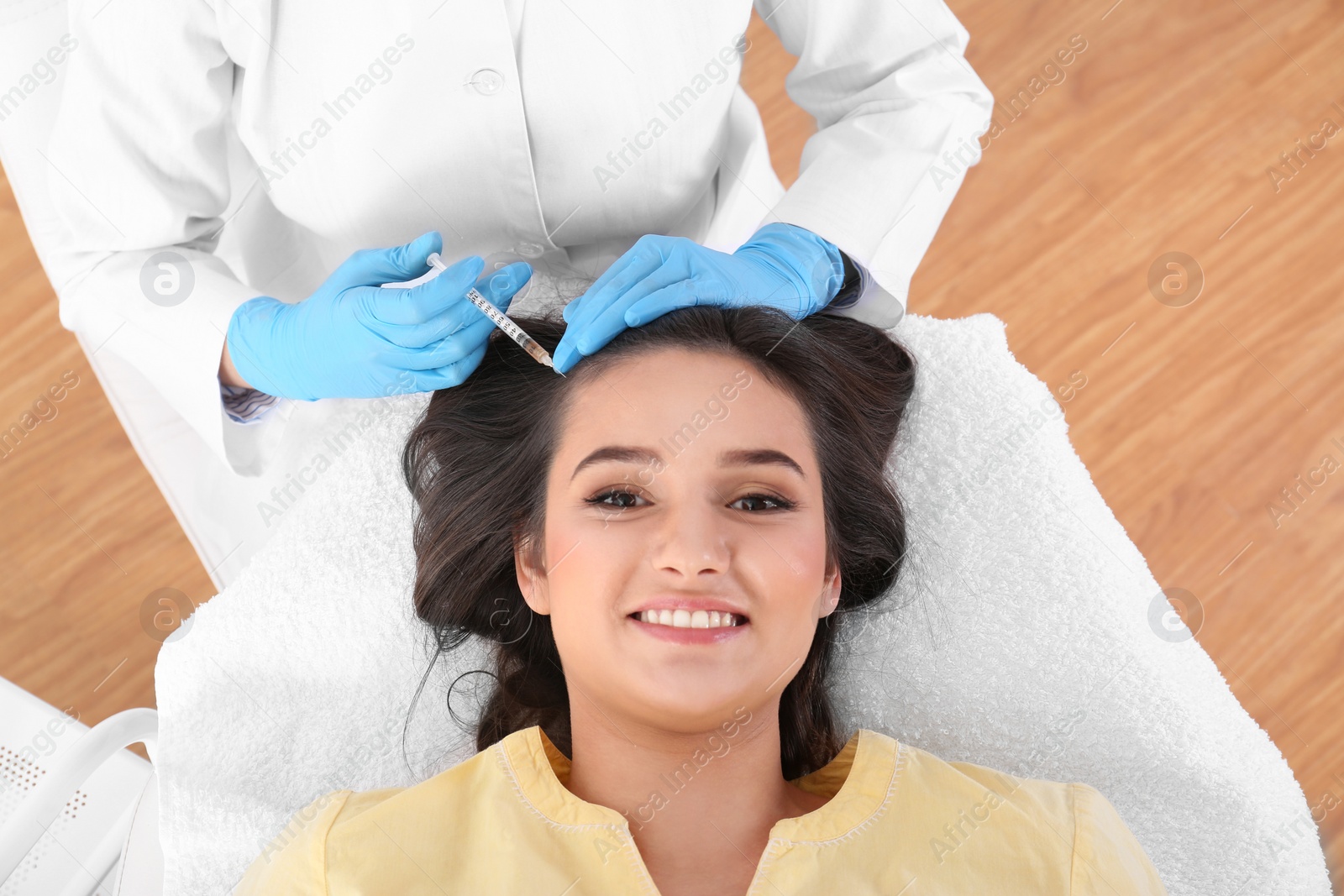 Photo of Young woman with hair loss problem receiving injection in salon, top view