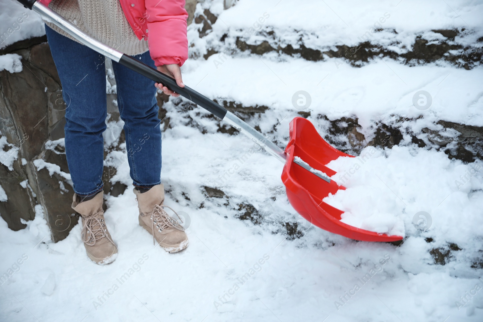 Photo of Woman cleaning stairs from snow with shovel outdoors on winter day, closeup