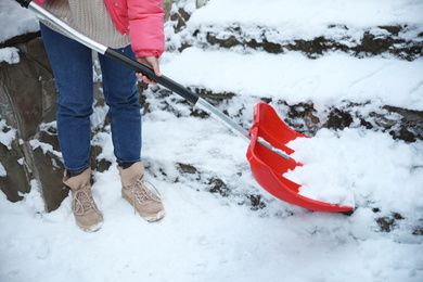 Woman cleaning stairs from snow with shovel outdoors on winter day, closeup