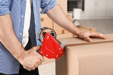 Photo of Man packing cardboard box indoors, closeup. Moving day