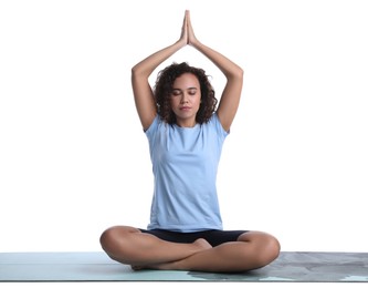 Photo of Beautiful African-American woman meditating on yoga mat against white background