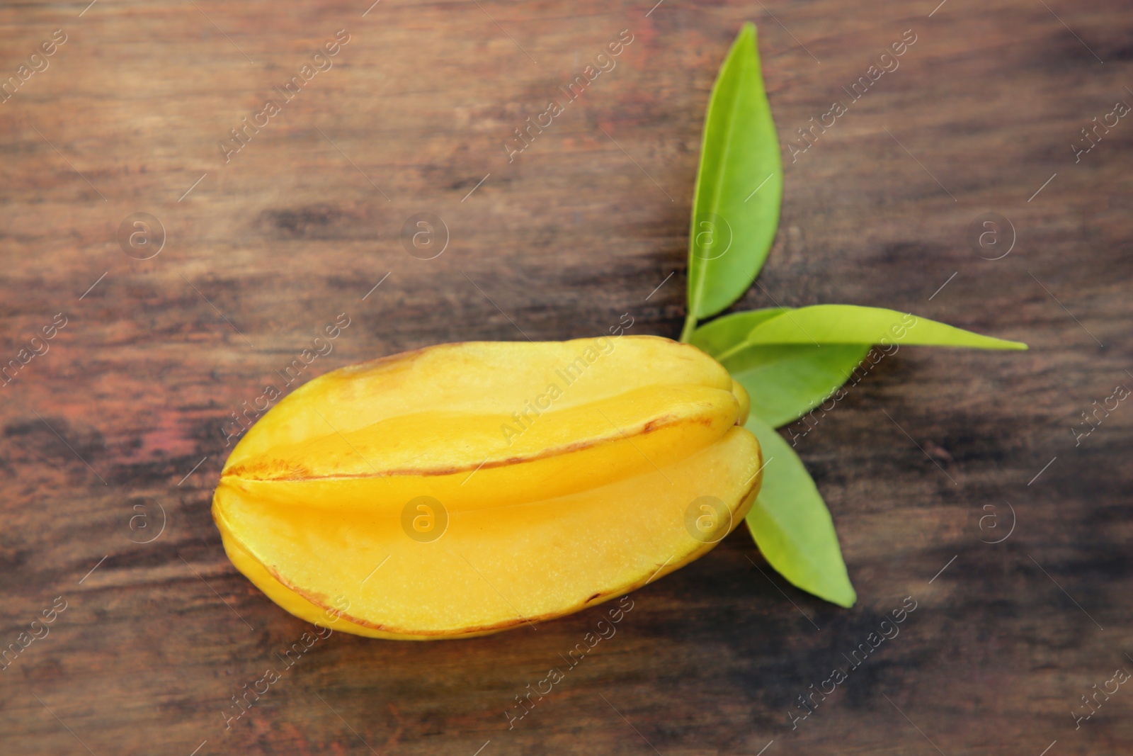 Photo of Delicious ripe carambola with leaves on wooden table