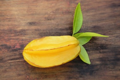 Photo of Delicious ripe carambola with leaves on wooden table