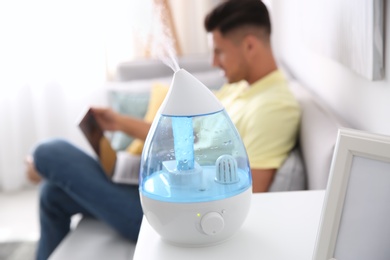 Photo of Modern air humidifier and blurred man on background