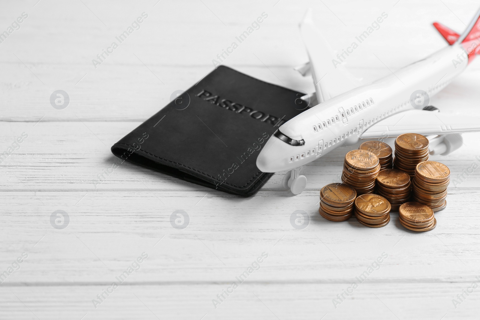 Photo of Plane model, passport and coins on white wooden background. Space for text