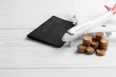 Photo of Plane model, passport and coins on white wooden background. Space for text
