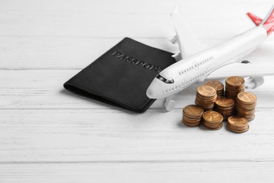 Plane model, passport and coins on white wooden background. Space for text