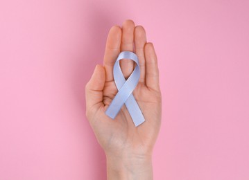International Psoriasis Day. Woman with light blue ribbon as symbol of support on pink background, top view