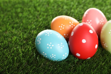 Photo of Colorful painted Easter eggs on green grass, closeup