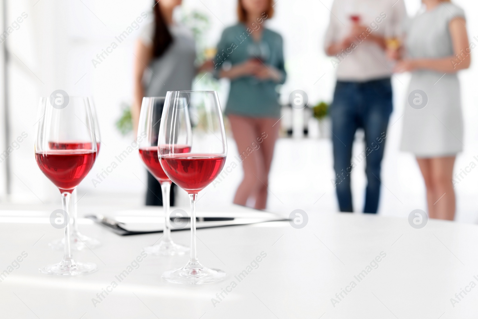 Photo of Glasses with delicious wine and blurred people on background