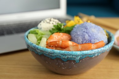 Delicious poke bowl served on wooden table, closeup