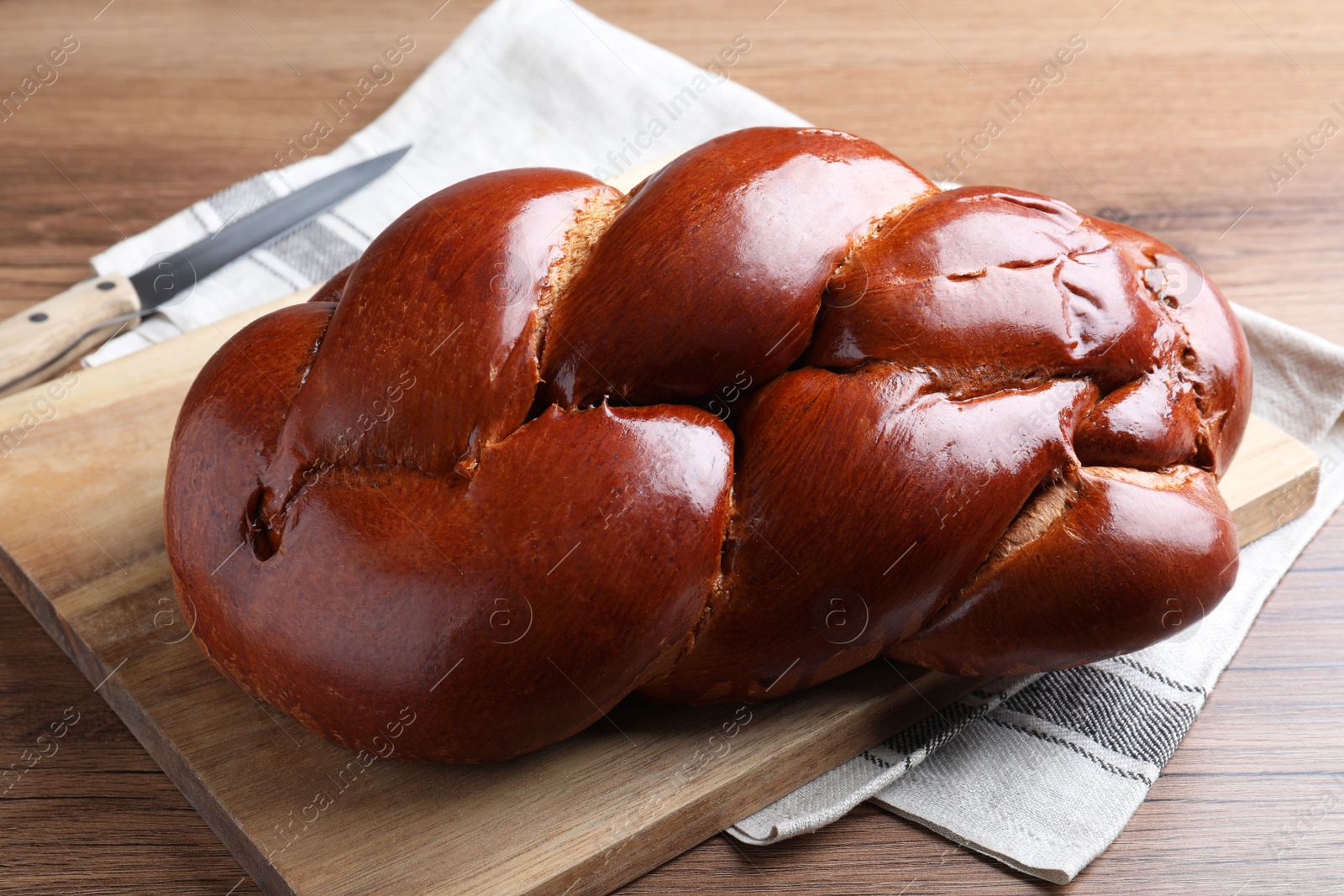 Photo of Homemade braided bread on wooden table, closeup. Traditional Shabbat challah