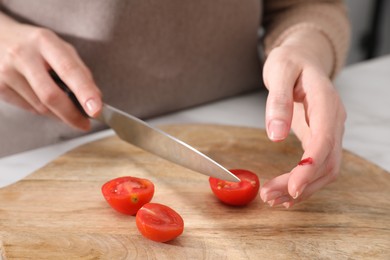 Woman cut finger while cooking in kitchen, closeup