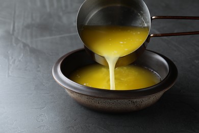 Photo of Pouring clarified butter into bowl on black table