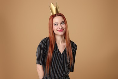 Beautiful young woman with princess crown in dress on beige background