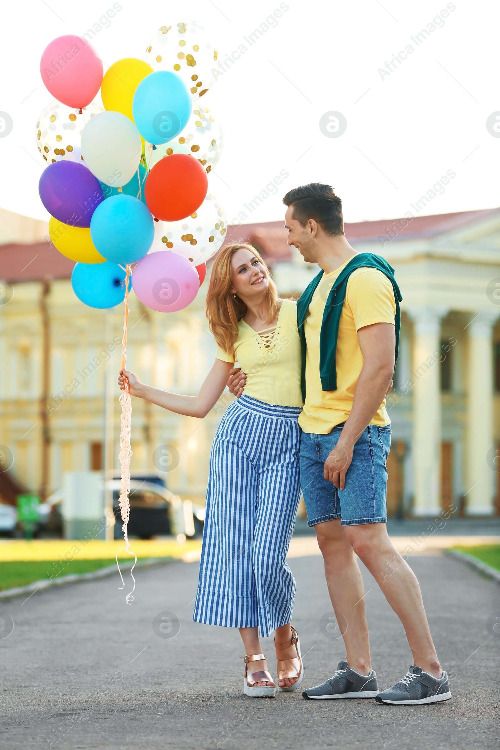 Photo of Young couple with colorful balloons outdoors on sunny day