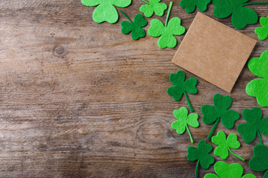 Photo of Flat lay composition with clover leaves on wooden table, space for text. St. Patrick's Day celebration