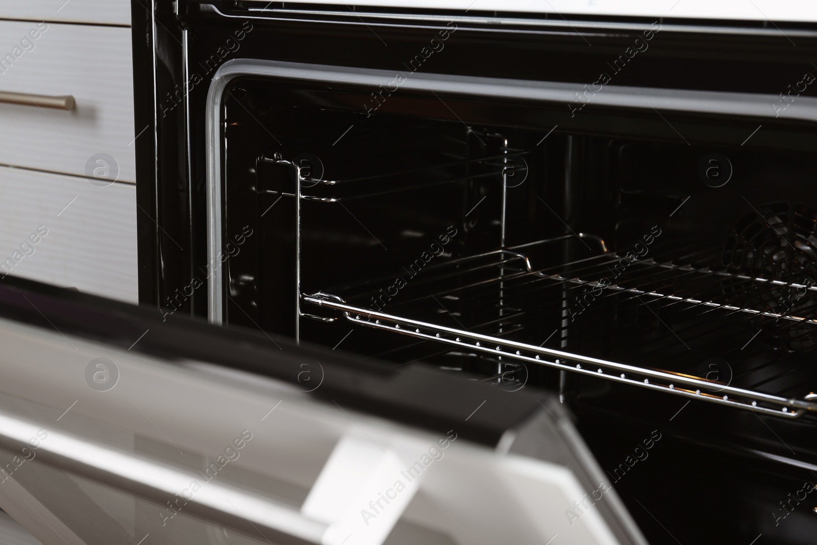 Photo of Open empty electric oven with rack, closeup