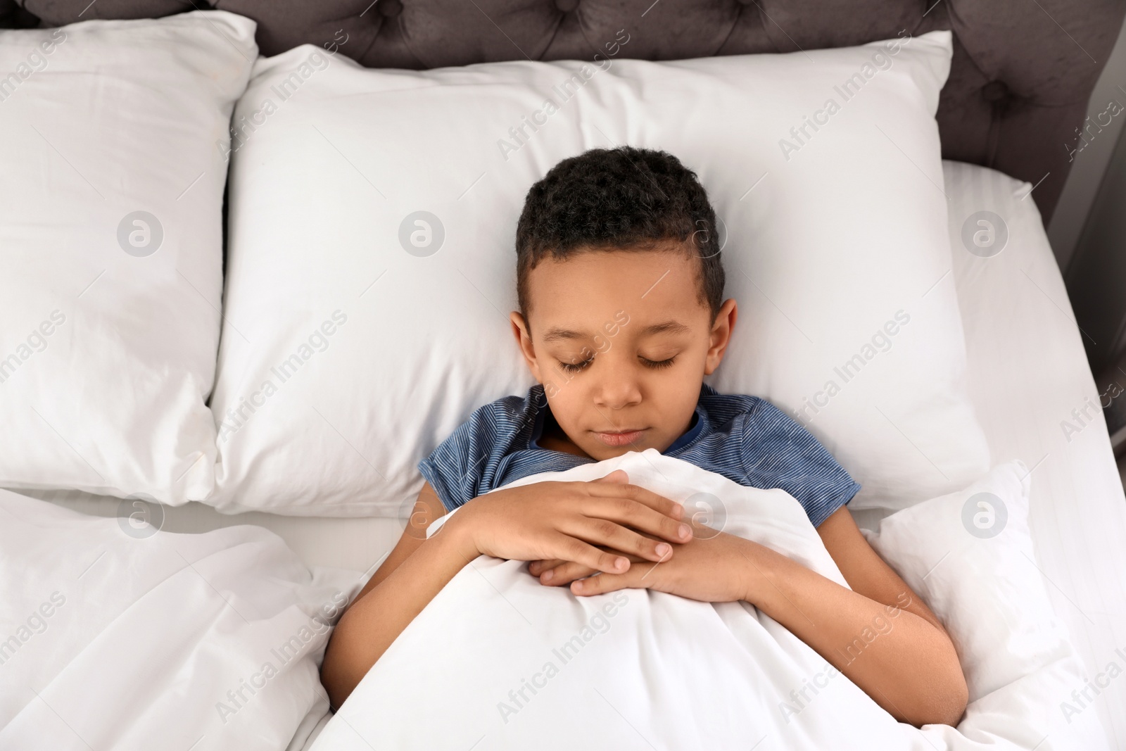 Photo of Cute little African-American boy sleeping in bed