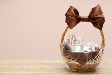 Photo of Wicker gift basket with cosmetic products on wooden table. Space for text