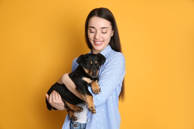 Photo of Young woman with cute puppy on yellow background