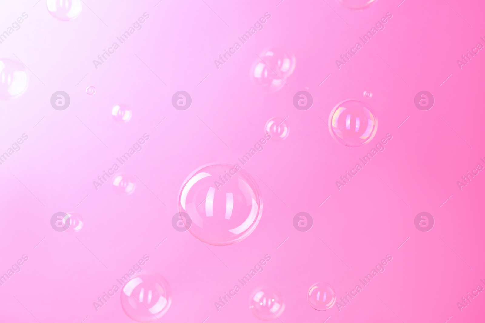 Photo of Beautiful transparent soap bubbles on pink background