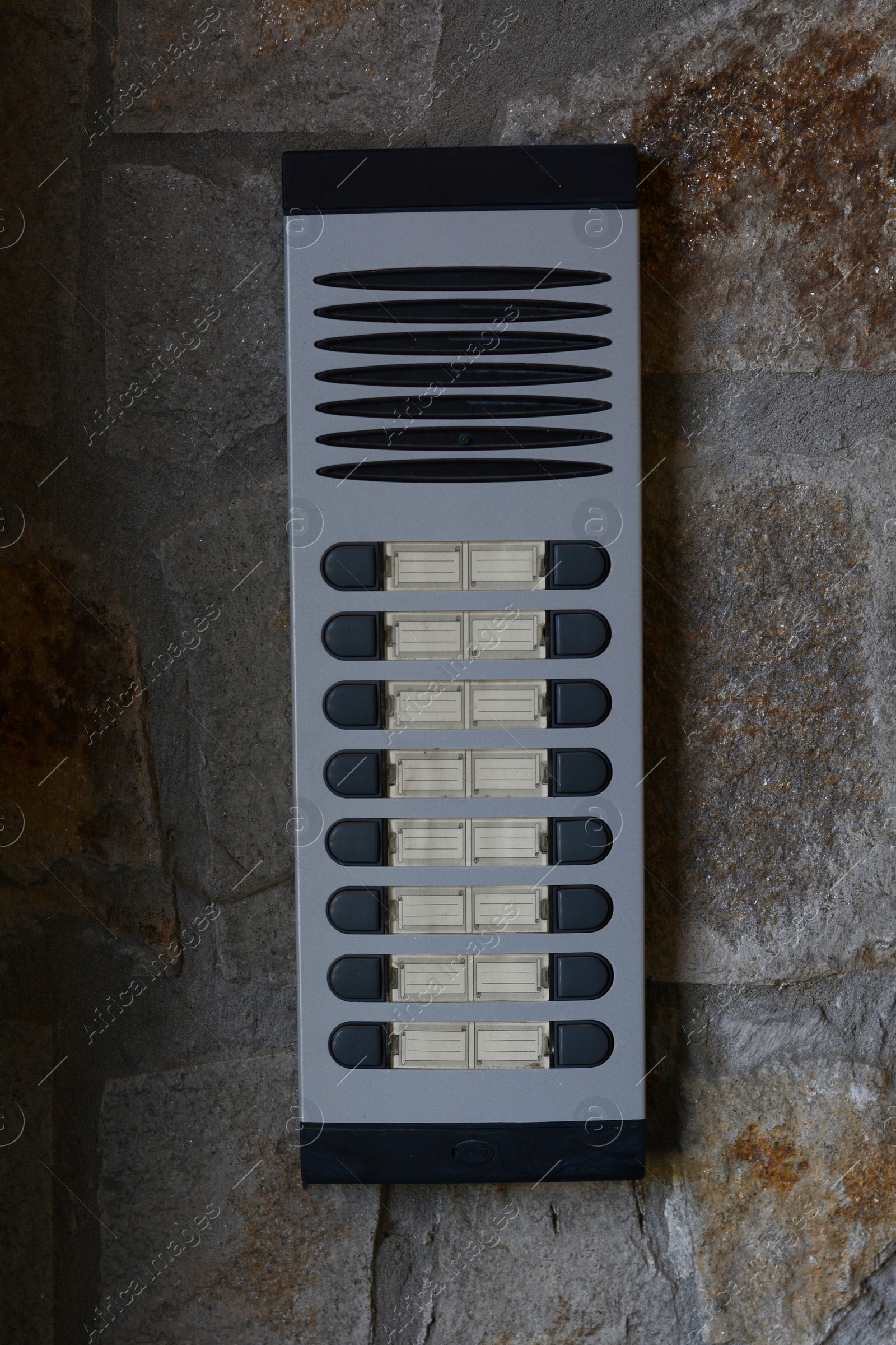 Photo of Modern intercom on concrete wall with stone fragments. Security system