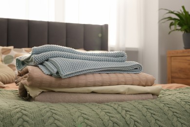 Photo of Stack of different folded blankets on bed in room. Home textile