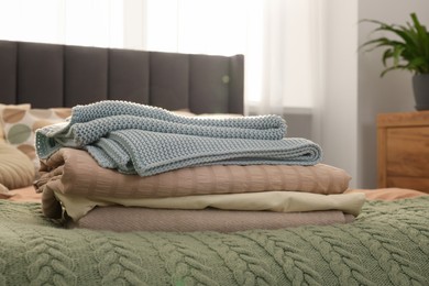 Stack of different folded blankets on bed in room. Home textile