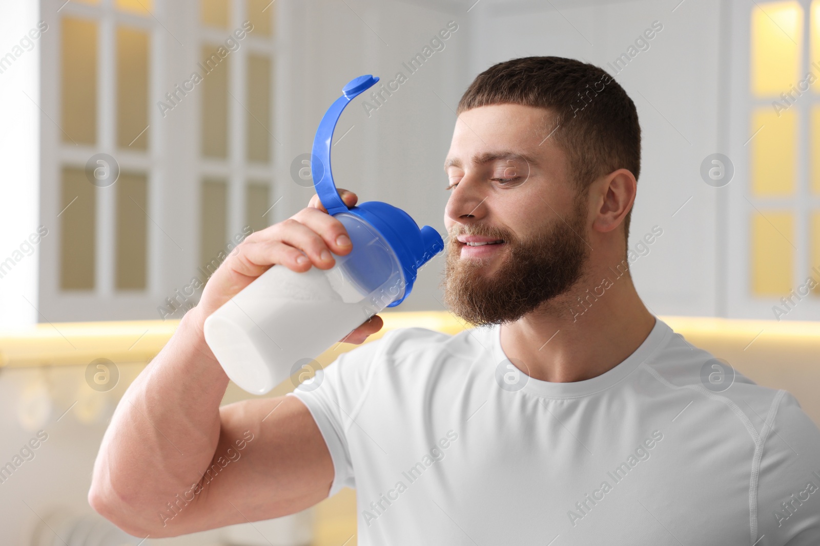 Photo of Young man with shaker of protein in kitchen