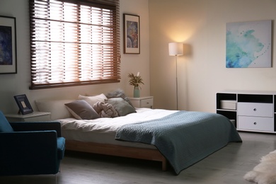 Photo of Modern room interior with comfortable double bed and window blinds