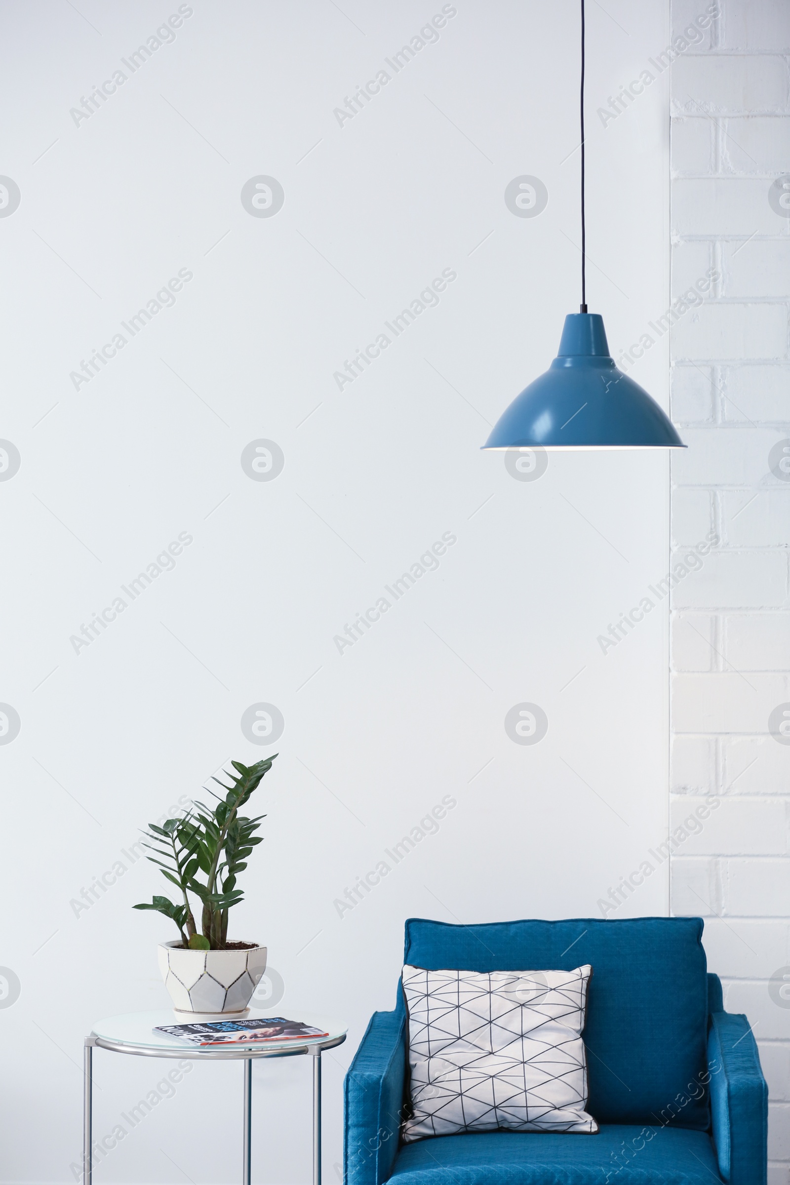 Photo of Modern lamp with plant on table and armchair indoors