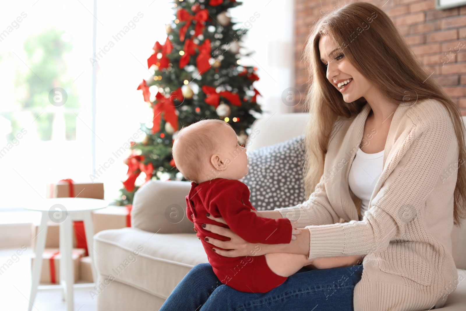 Photo of Young woman with baby celebrating Christmas at home