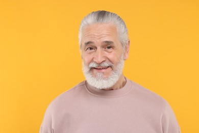 Portrait of handsome senior man on orange background