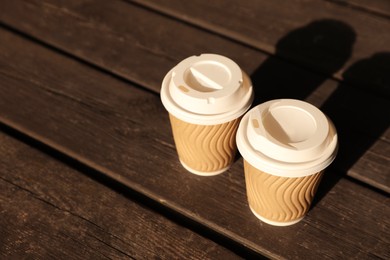 Paper cups on wooden table, space for text. Coffee to go