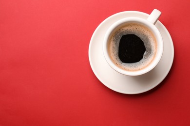 Photo of Fresh coffee in cup on red background, top view. Space for text