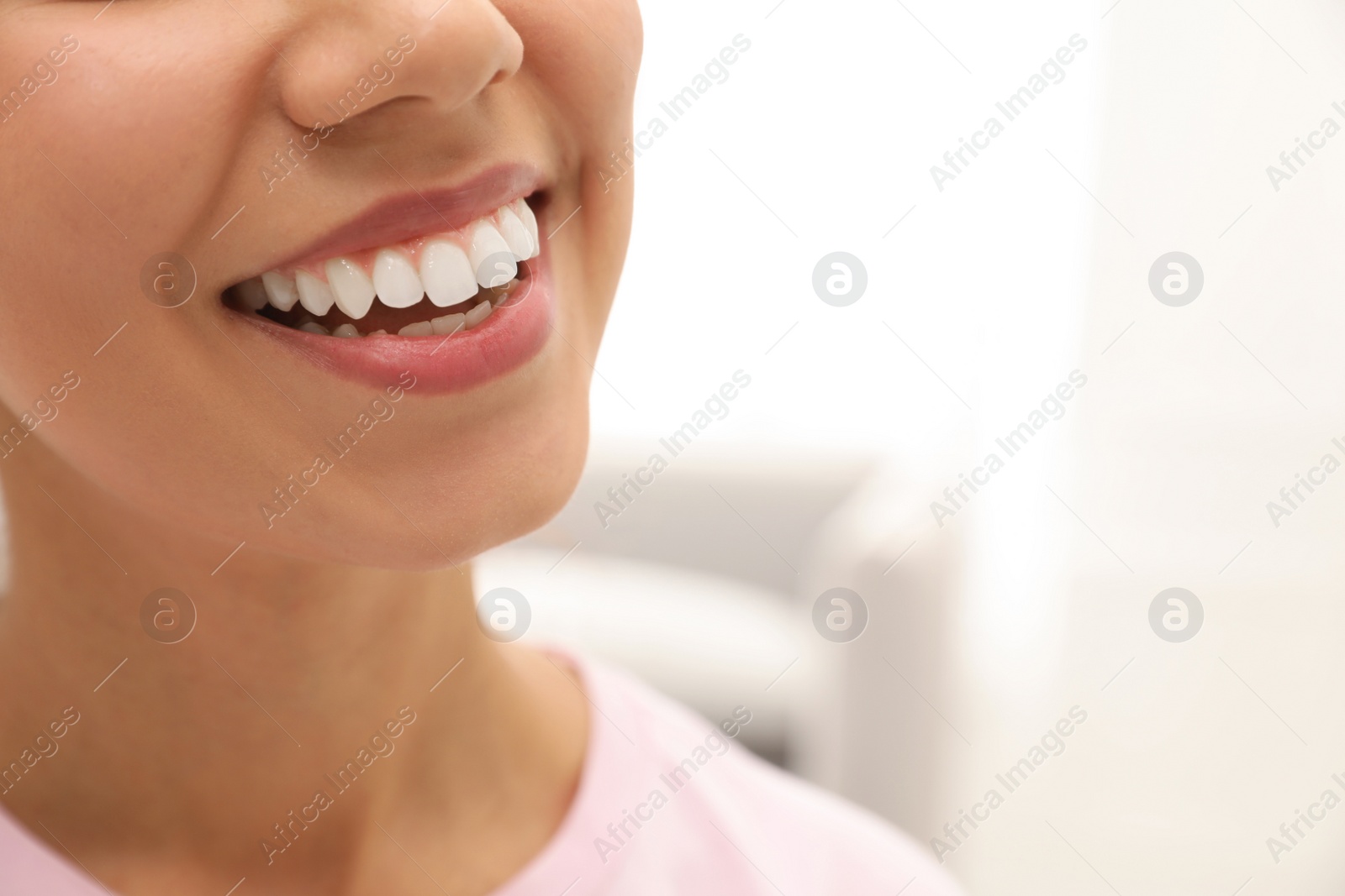 Photo of Young woman with healthy teeth on blurred background, closeup. Space for text