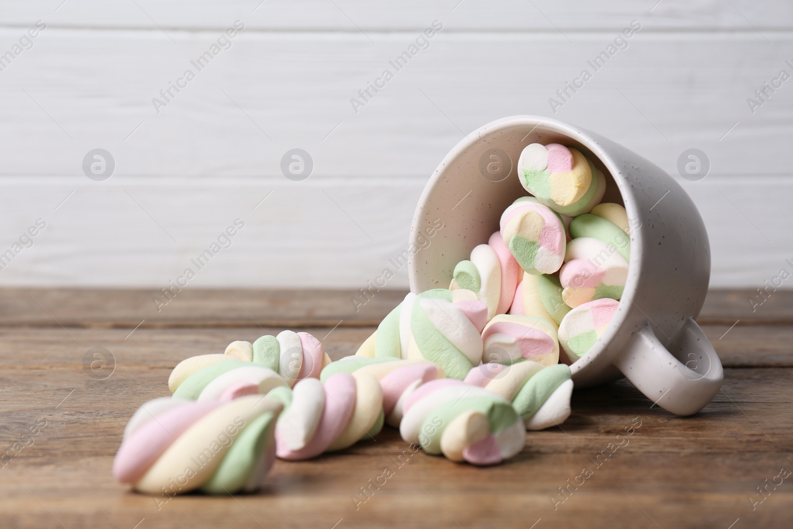 Photo of Ceramic cup with colorful marshmallows on wooden table