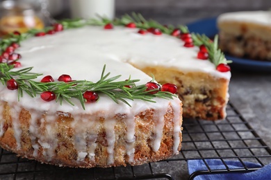 Photo of Traditional Christmas cake decorated with rosemary and pomegranate seeds on grey table, closeup