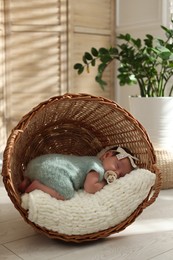 Photo of Adorable newborn baby with pacifier sleeping in overturned wicker basket at home