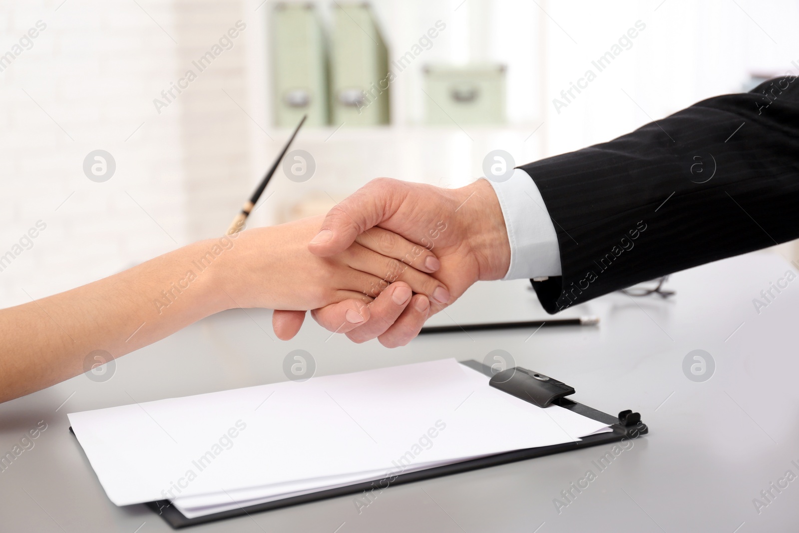 Photo of Lawyer shaking hands with client in office, closeup