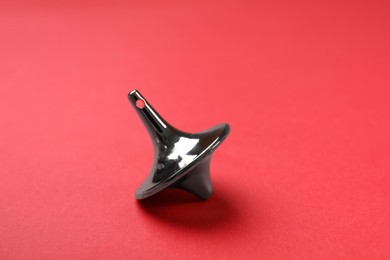 Photo of One silver spinning top on red background, closeup